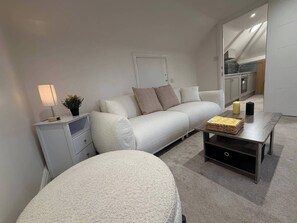 Een moderne woonkamer met een bank, een salontafel, een lamp en een bijzettafeltje.
