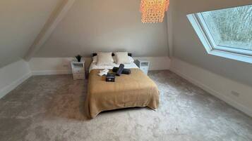 A bedroom with a bed, bedside tables, a lamp, and a window.