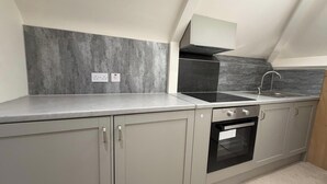 Una cocina moderna con armarios grises, una estufa negra y un protector contra salpicaduras gris.