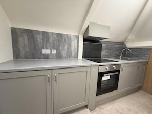 A modern kitchen with grey cabinets, a black stove, and a grey backsplash. - 1 Bed - Sleeps 2 - Free Parking (London)