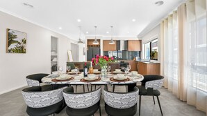 A modern dining area with a marble table, black and white patterned chairs, and a vase of red flowers. - Park-fronted Luxury Grand Family House with Gym, Heated Pool/Spa, Tennis Court. (Mambourin)
