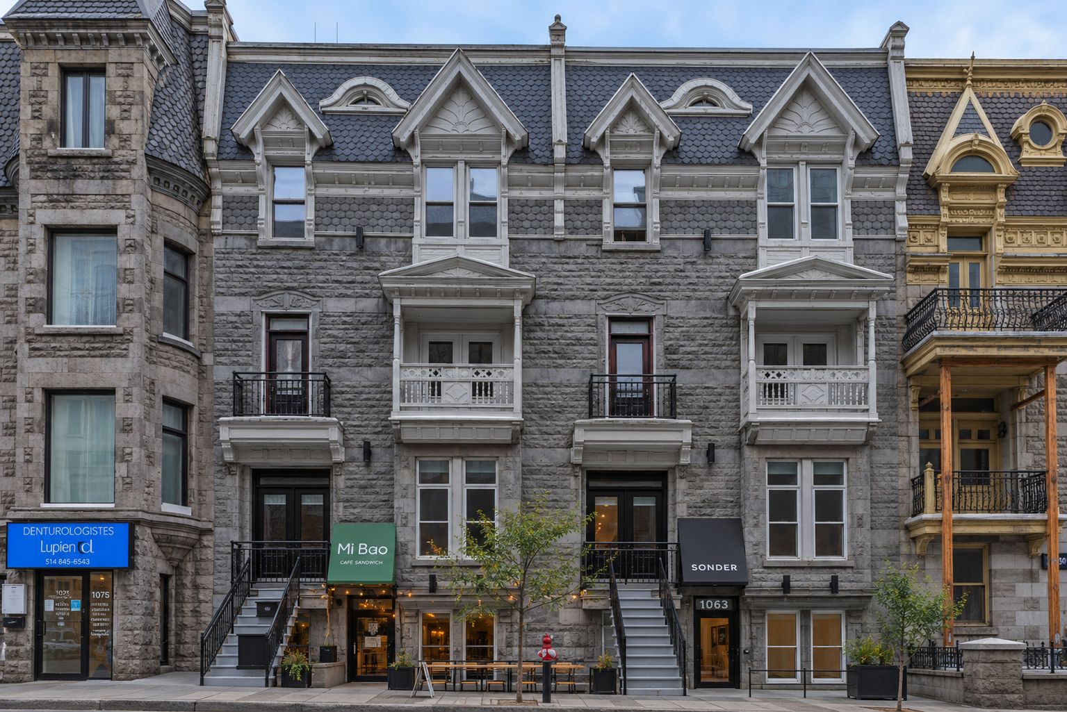 A row of townhouses with multiple stories, each featuring a balcony and a set of stairs leading to the entrance.