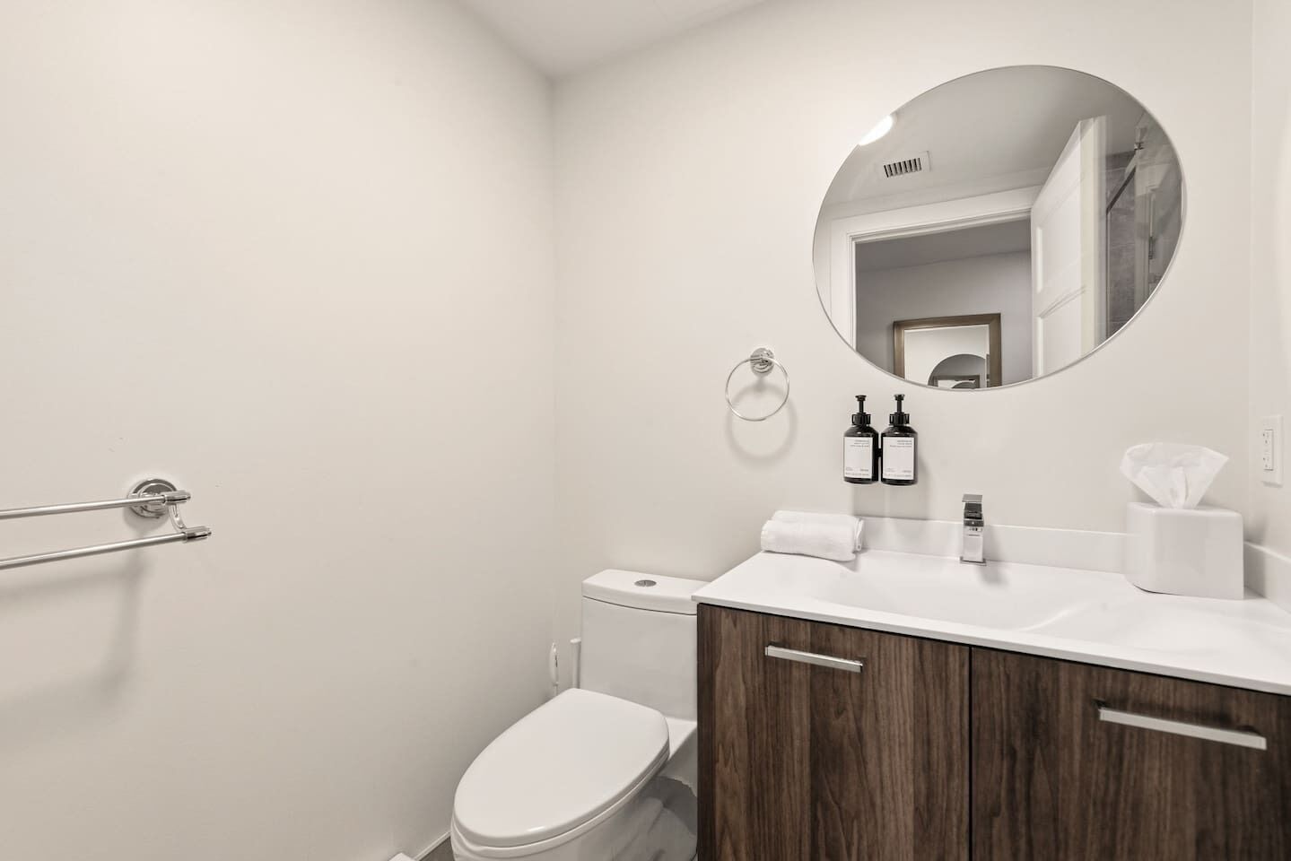 Ein modernes Badezimmer mit Toilette, Waschbecken, Spiegel und Handtuchhalter.