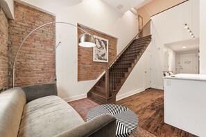Een modern interieur met een bakstenen muur, een trap, een bank en een keukenhoek.