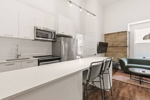 Eine moderne Küche mit weißen Schränken, Edelstahlgeräten und einer Bar mit Hockern.