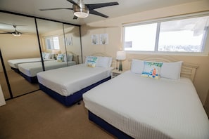 A hotel room with two beds, a ceiling fan, a window, and artwork on the walls. - ONE BEDROOM CONDO 1107 (San Diego)