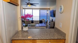 Eine Küche mit Granit-Arbeitsplatten, Holzschränken, einem weißen Kühlschrank und einem Topf mit einer Orchidee.