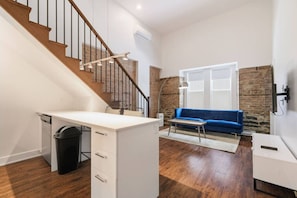 Eine moderne Wohnung mit Treppe, einem weißen Schreibtisch, einem blauen Sofa und einer Ziegelwand.