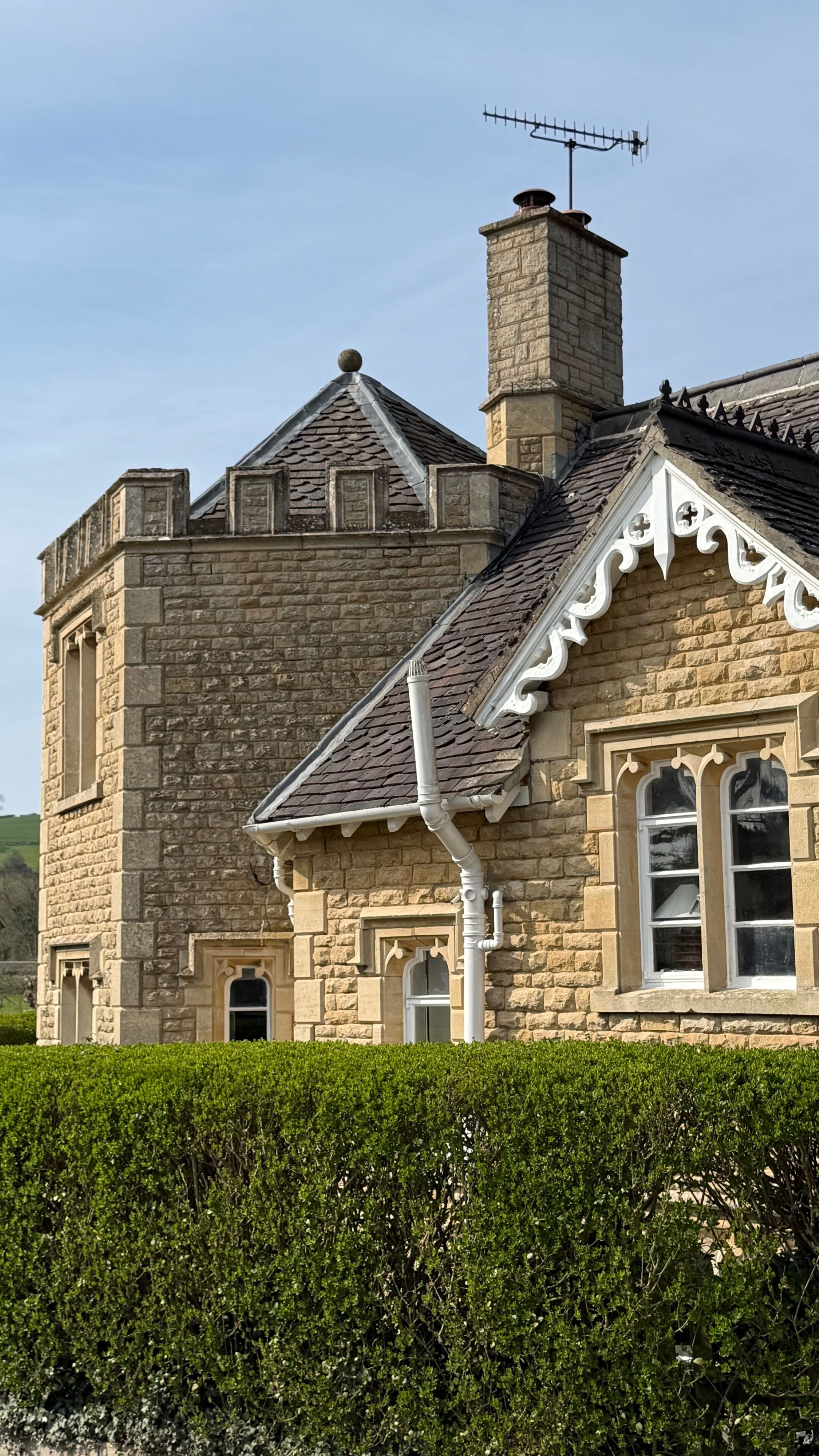 A stone building with a chimney, a pointed roof, and a window with a decorative frame.