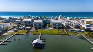 A coastal hotel with multiple buildings, a swimming pool, and a dock. - 2BR with loft, sleeps 8, lagoon front, pool & private beach access (Gulf Shores)