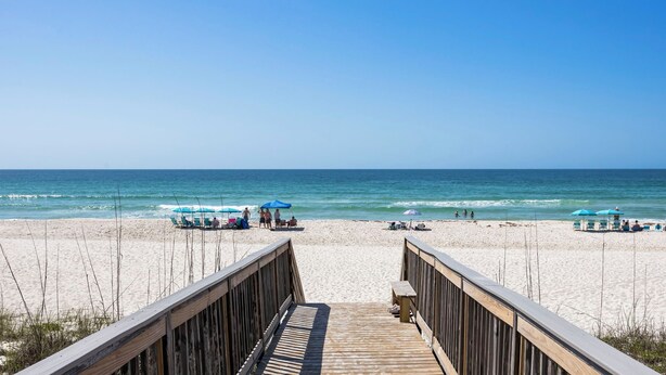 A wooden boardwalk leading to a beach with umbrellas and chairs. - 2BR with loft, sleeps 8, lagoon front, pool & private beach access (Gulf Shores)