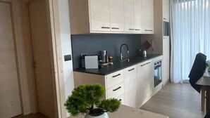 A modern kitchen with white cabinets, a black countertop, and a small potted plant. - Bormio Apartments al pradais  giardino est  (Bormio)