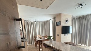 A modern kitchen with wooden cabinets, a dining area with a table and chairs, and a ceiling fan. - Bormio Apartments al pradais  giardino est  (Bormio)