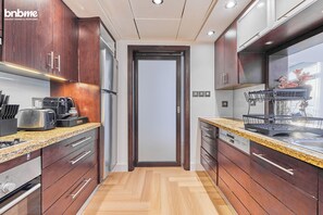 Een moderne keuken met houten kastjes, een granieten aanrechtblad, een ingebouwde vaatwasser en een roestvrijstalen koelkast.