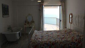 A bedroom with a bed, a bathtub, a ceiling fan, a dresser, and a view of the sea. - Your Mediterranean dream home  - Costapinosmar (Salou)