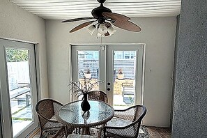A room with a ceiling fan, a glass table with chairs, and a door leading to an outdoor area. - 3-bedroom house in quaint Fernandina Beach with cool AC (Fernandina Beach)