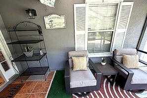 A sunlit porch with a metal bench, a small table, and a potted plant. - 3-bedroom house in quaint Fernandina Beach with cool AC (Fernandina Beach)