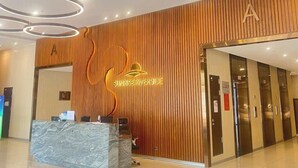 En hotellobby med träpanel på väggarna, en receptionsdisk i marmor och en logotyp ovanför disken.