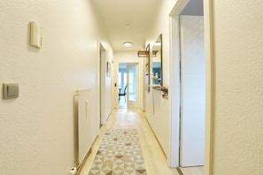 A hallway with a patterned floor, a radiator, a light switch, and a door leading to another room. - Residence on the hillside apartment 204 (Scharbeutz)