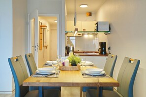 Een eettafel met stoelen, een kaars en een klein plantje als decoratie.