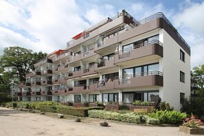 Een hotel met meerdere verdiepingen, balkons, een tuin en een heldere lucht.