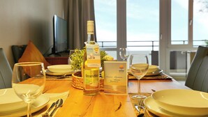 Ein Esstisch ist gedeckt mit Tellern, Besteck, einer Weinflasche und einem Glas.