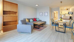 Ein modernes Wohnzimmer mit Sofa, Couchtisch und Essbereich.