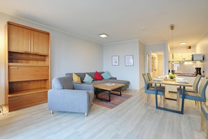A modern living room with a sofa, coffee table, and dining area. - Residence on the hillside apartment 204 (Scharbeutz)
