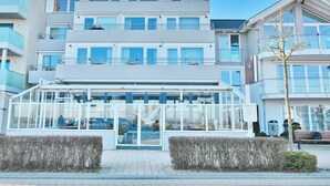 Un edificio moderno con entrada de cristal, varios pisos y balcones.