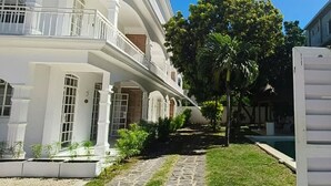 A white building with a stone pathway leading to a pool. - La Maison Coloniale II (Grand Baie)
