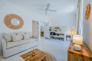 En moderne stue med en hvid sofa, et træbord og en loftsvifte.