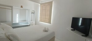 Ein Hotelzimmer mit Bett, Fernseher, Spiegel, Fenster und Kleiderschrank.