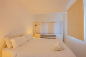 Et hotelværelse med seng, skab og spejl.