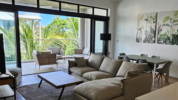 A modern living room with a sofa, coffee table, and dining area. - Sublime Pointe aux Canonniers (Pointe aux Canonniers)