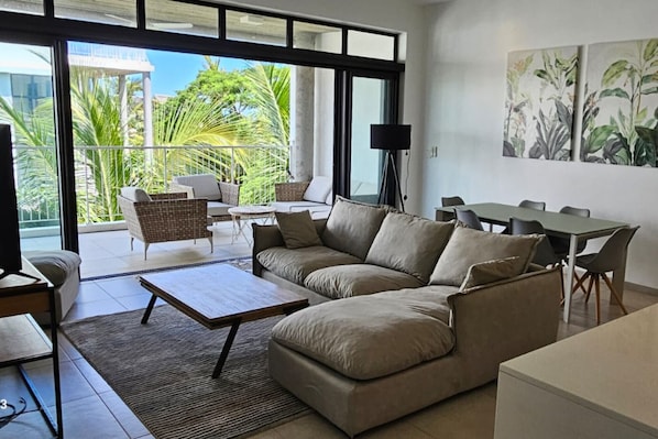 A modern living room with a sofa, coffee table, and dining area.