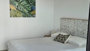 A bedroom with a bed, a headboard, a nightstand, a pillow, and a wall-mounted painting. - Sublime Pointe aux Canonniers (Pointe aux Canonniers)