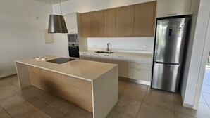 A modern kitchen with a central island, stainless steel appliances, and light wood cabinetry. - Sublime Pointe aux Canonniers (Pointe aux Canonniers)