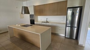 A modern kitchen with a central island, stainless steel appliances, and light wood cabinetry.
