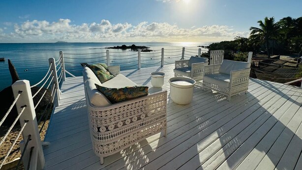 A wooden deck with wicker furniture and a view of the ocean. - Villa Anse Turquoise - Breathtaking sea view (Anse La Raie)