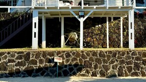 A white building with a red roof, a stone wall, and a staircase leading up to it. - Villa Anse Turquoise - Breathtaking sea view (Anse La Raie)