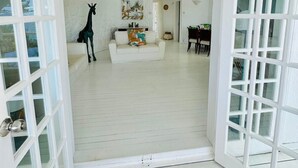 An open doorway leading to a living room with a white sofa, a giraffe statue, and a painting on the wall. - Villa Anse Turquoise - Breathtaking sea view (Anse La Raie)