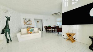 A spacious living area with a white sofa, a giraffe sculpture, and a dining table with chairs. - Villa Anse Turquoise - Breathtaking sea view (Anse La Raie)
