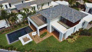 Un moderno edificio residencial de varios pisos con piscina, terraza de madera y exuberante jardinería.