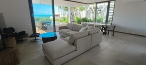 Ein modernes Wohnzimmer mit einer Couch, einem runden Couchtisch und einem Essbereich mit Tisch und Stühlen.