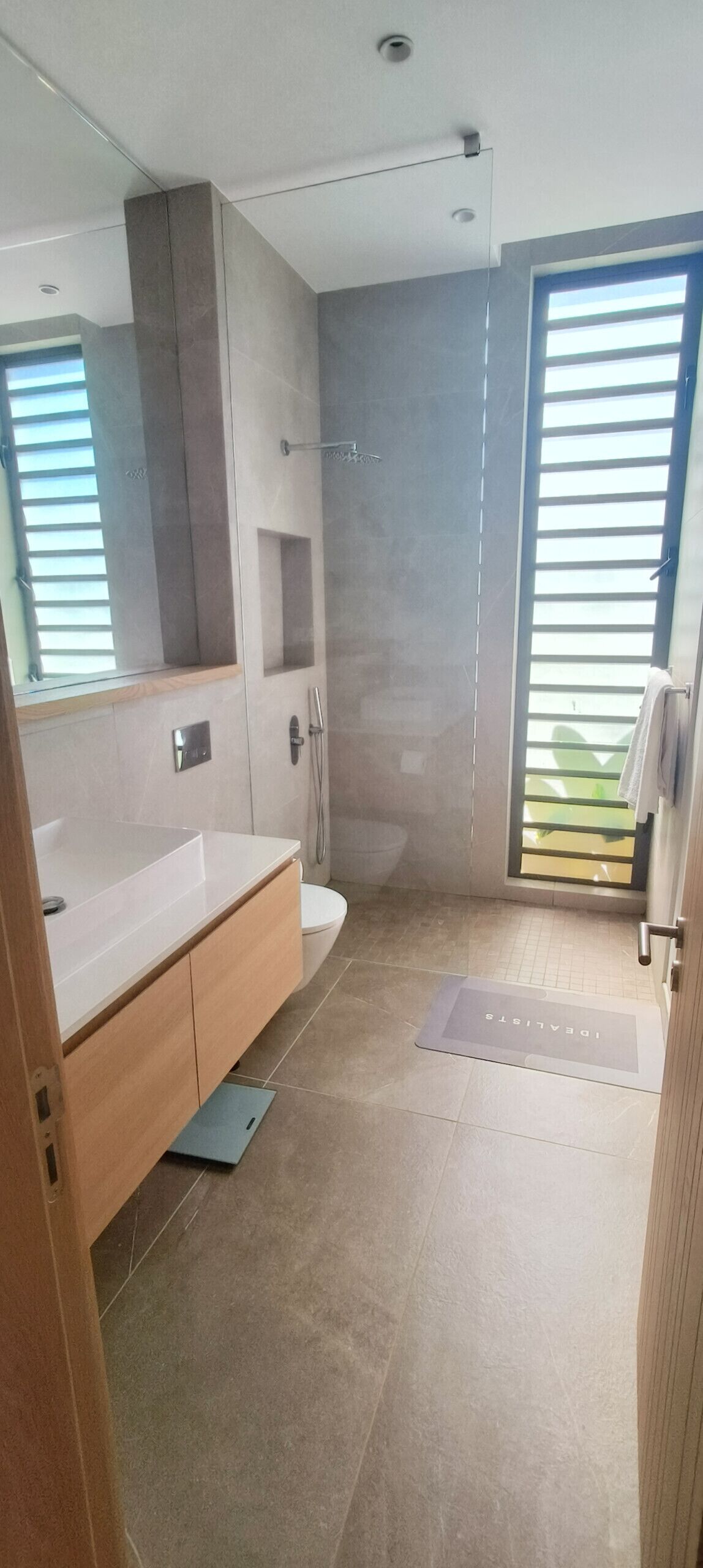 Une salle de bain moderne avec un grand miroir, une baignoire, une douche et des toilettes.