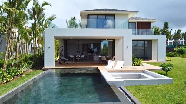 Una casa moderna de dos pisos con piscina, mobiliario exterior y un porche acristalado.