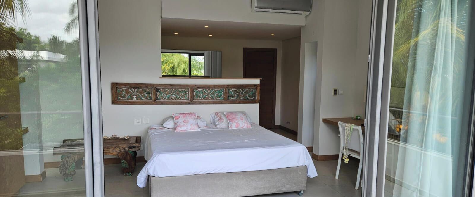 A bedroom with a bed, a window, a door, and a small table.