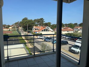 Ein Balkon mit Blick auf einen Parkplatz, ein Restaurant und Wohnhäuser.