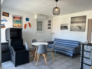 Ein gemütlicher Wohnbereich mit einer Couch, Sesseln, einem kleinen Tisch und einer Deckenleuchte.