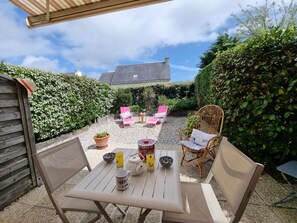 An outdoor patio with a table set for two, surrounded by wicker chairs and a small table with a teapot, cups, and a bowl. - House near the beach, pets welcome - 4 guests (Sarzeau)